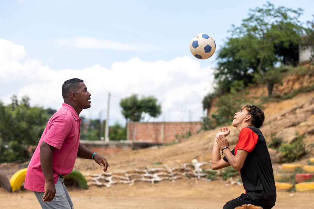 Participantes del Programa Familia Fuertes. Padre e hijo juegan fútbol.