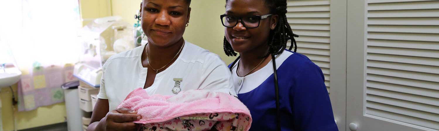 Mother and newborn in hospital setting standing with a nurse by their side