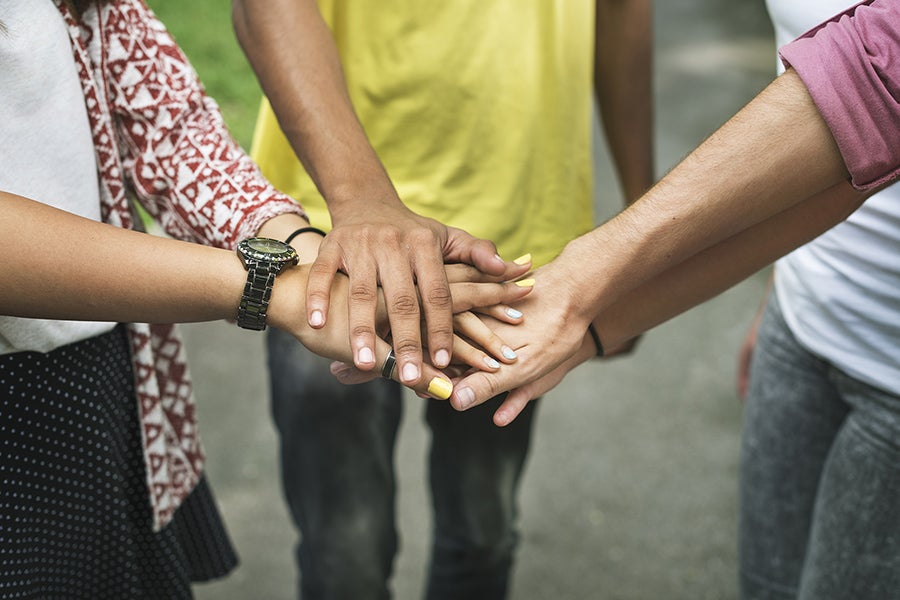 Diverse teens placing hands in the center.