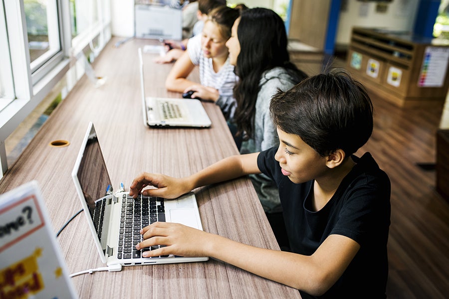 Young students engaging with laptops in a classroom.