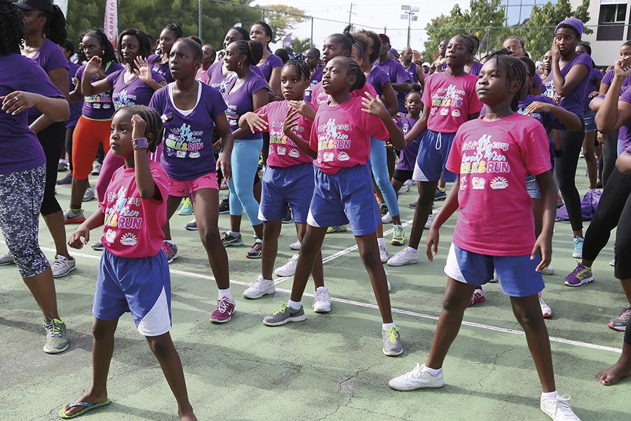 Group of young girls participating in a runathon standing outside dancing.