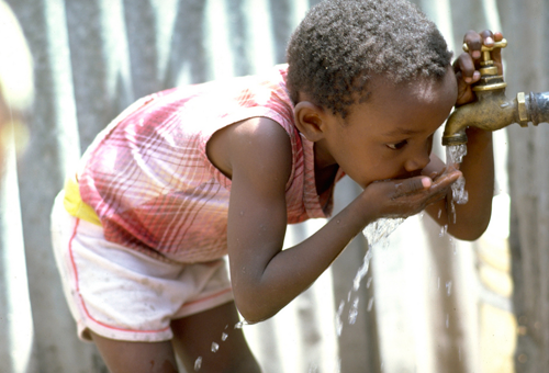 child drinking water from faucet in Haiti