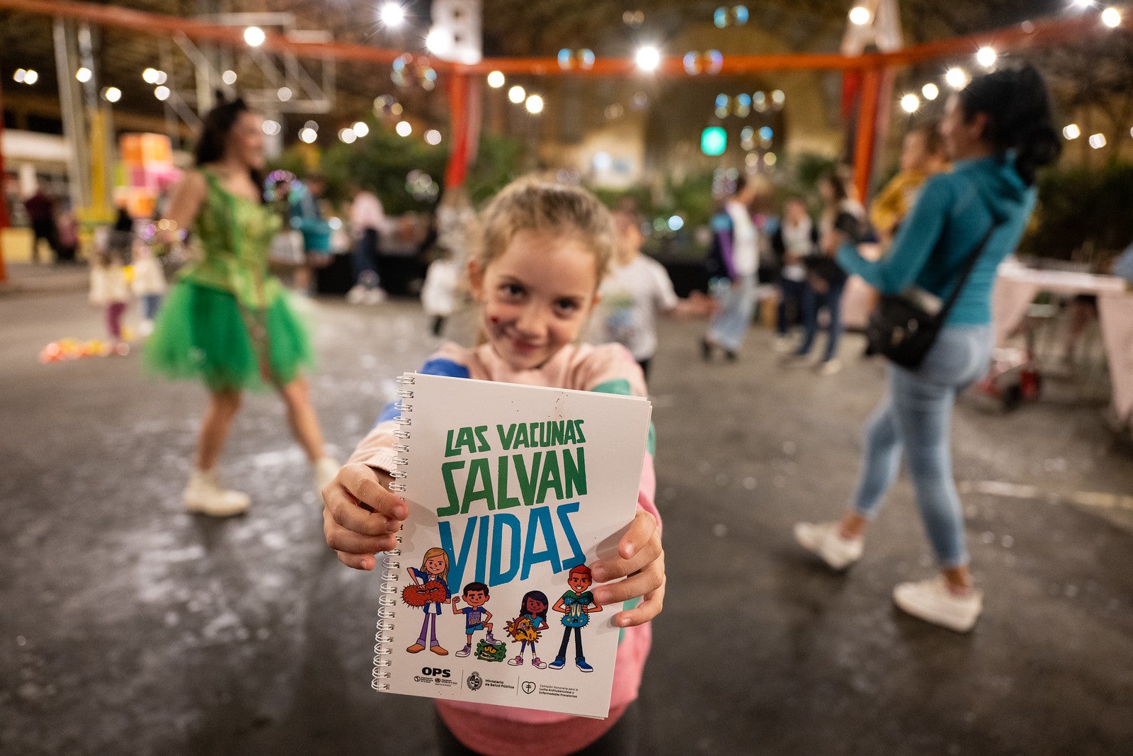A girl holds up a sign in Spanish that says: 'Vaccines save lives'