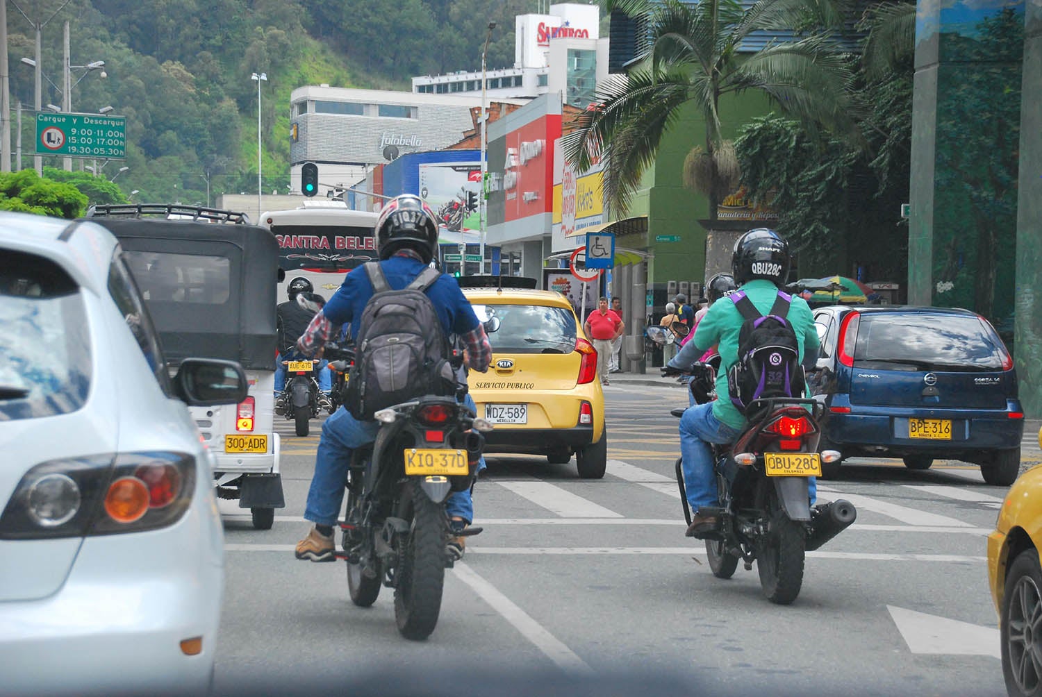 Vehicles and motorcycles on a street, motorcyclists wearing helmets