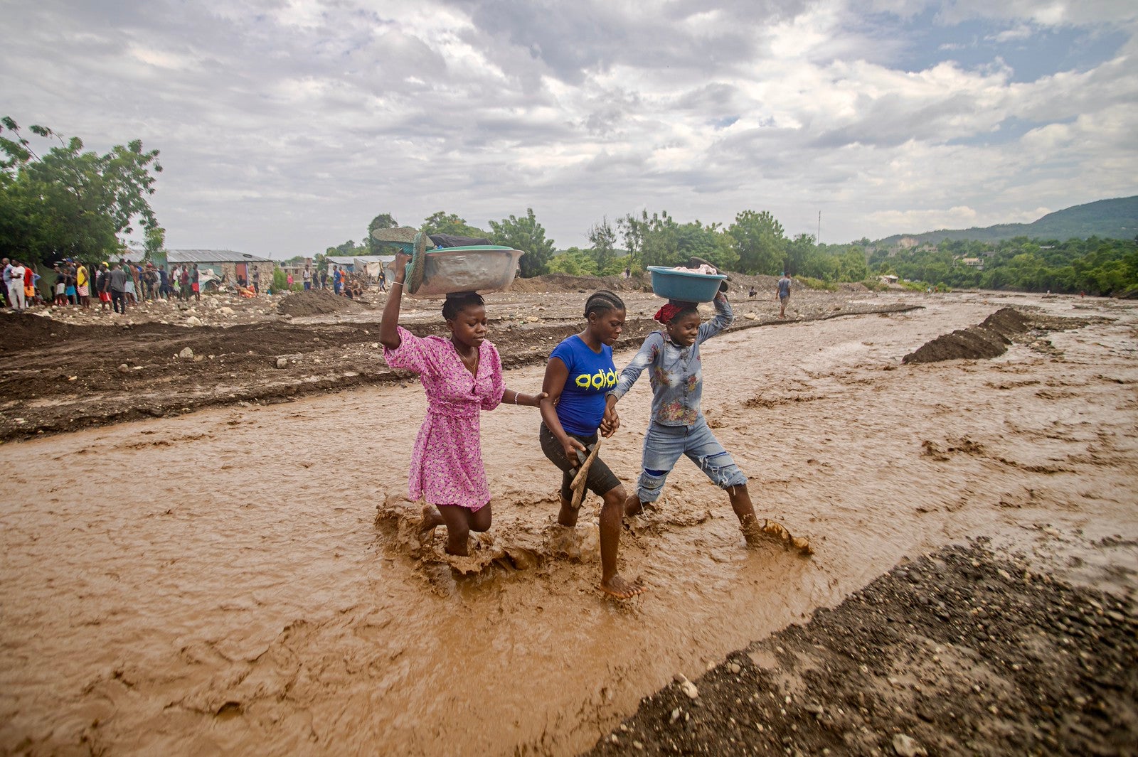 No Haiti, as pessoas atravessam uma estrada inundada após a passagem do furacão Melissa.
