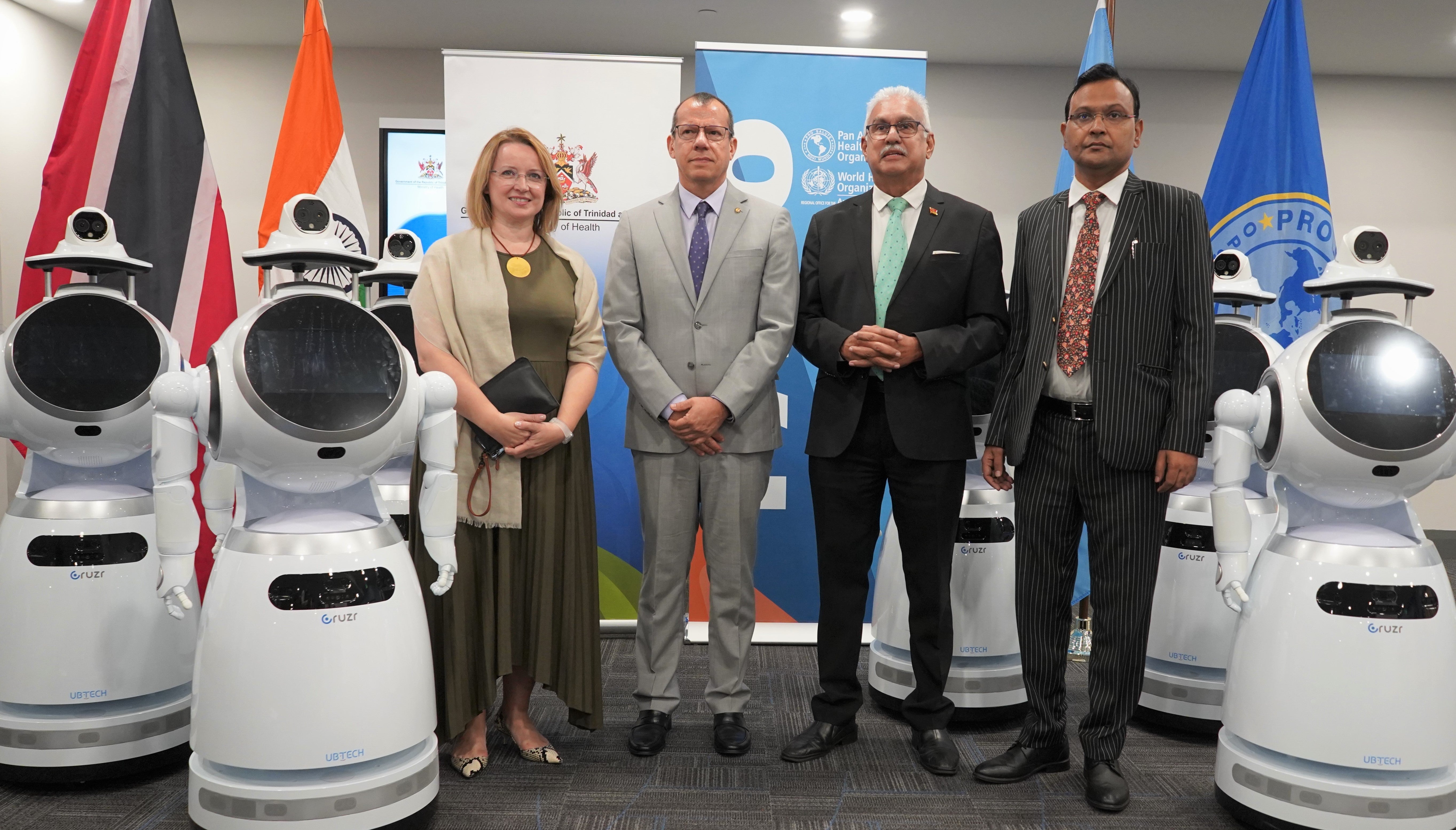 (L – R) Mz. Joanna Kazana - United Nations Resident Coordinator for Trinidad and Tobago, Dr. Gabriel Vivas Francesconi -  PAHO/WHO Representative for Trinidad and Tobago and the Dutch Caribbean Islands, The Honourable Terrence Deyalsingh -  Minister of Health and His Excellency Dr. Pradeep Singh Rajpurohit -  High Commissioner of India to the Republic of Trinidad and Tobago stand among the Humanoid Health Service Robots.