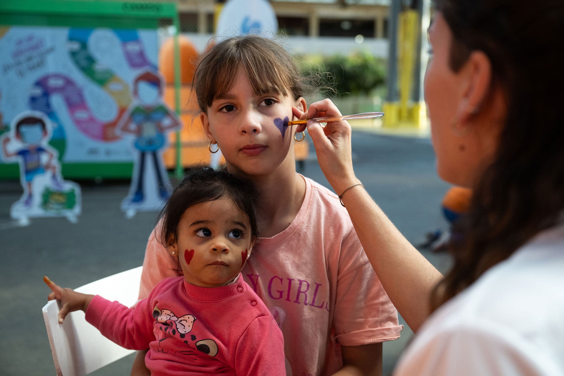 mujer pinta la cara a dos niñas