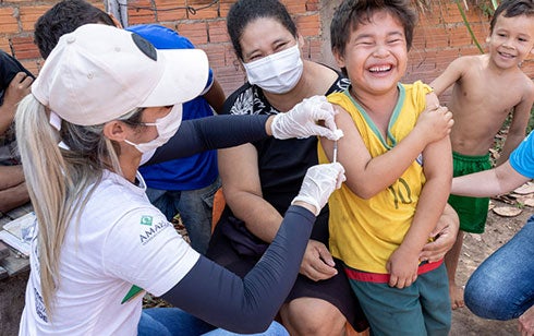 Boy being vaccinated surrounded by children