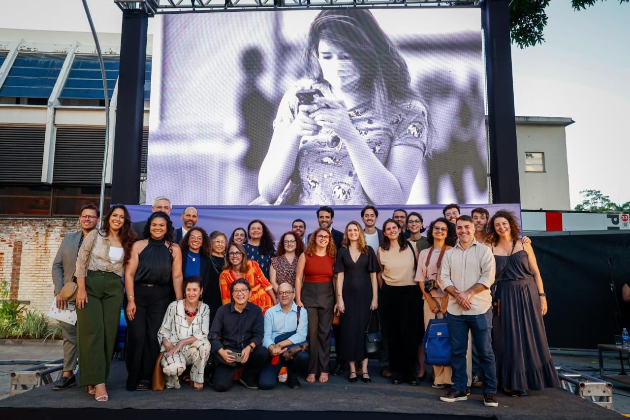 A group of authorities, researchers, and participants gathered around the inauguration plaque during the reopening ceremony of the Cultural Center of the Ministry of Health in Rio de Janeiro. Some people applaud as the commemorative plaque is unveiled; in the foreground, a man in a wheelchair smiles and takes part in the moment.