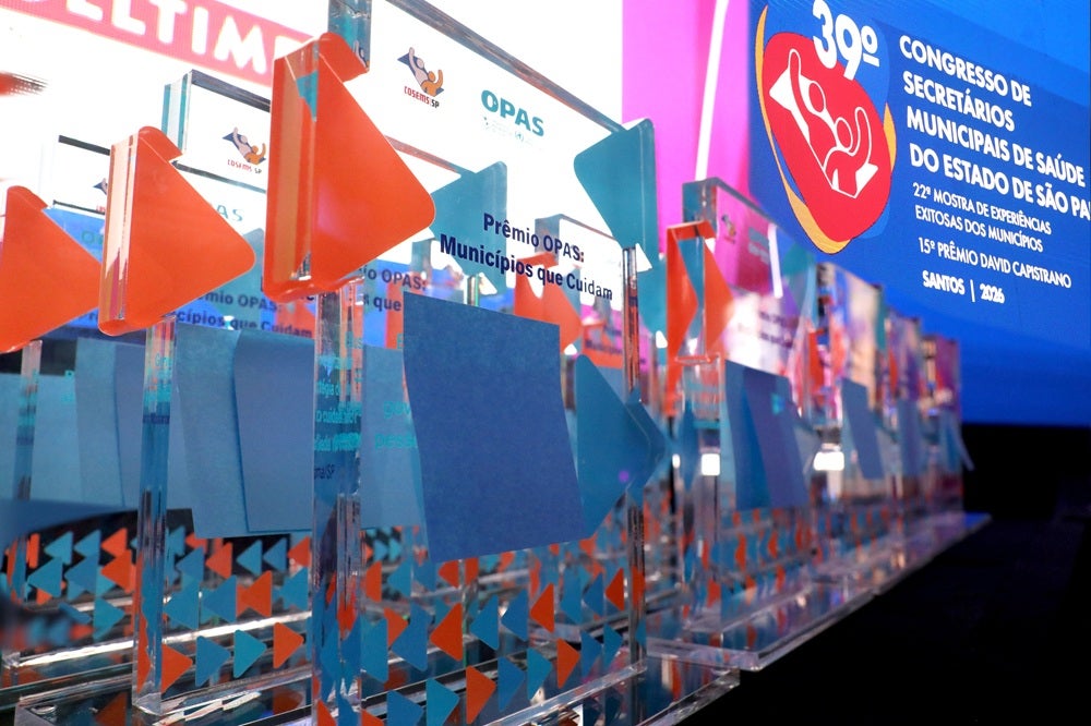 Imagem do prêmio e, ao fundo, a identidade visual do 39º Congresso de Secretários Municipais de Saúde do Estado de São Paulo