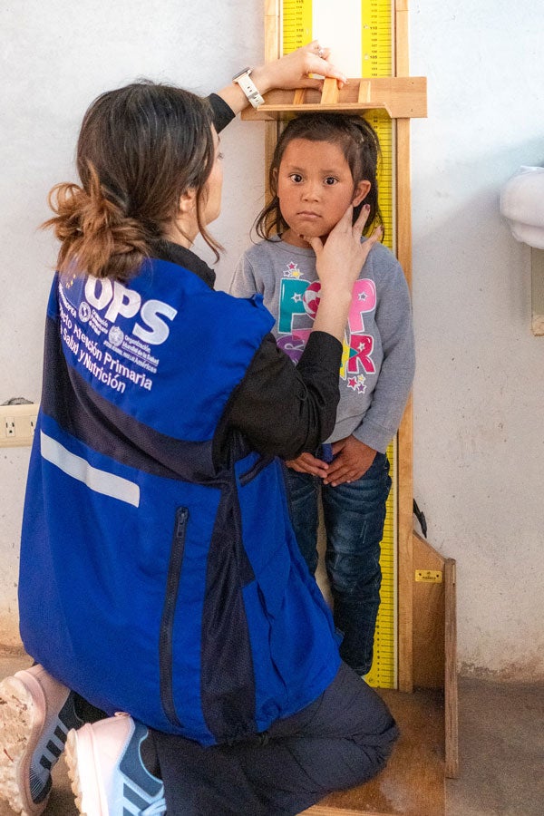 Health worker checks the height of a young girl