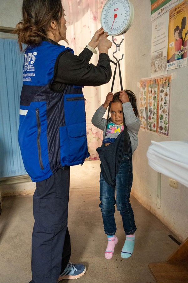 PAHO worker checks the weight of a young girl