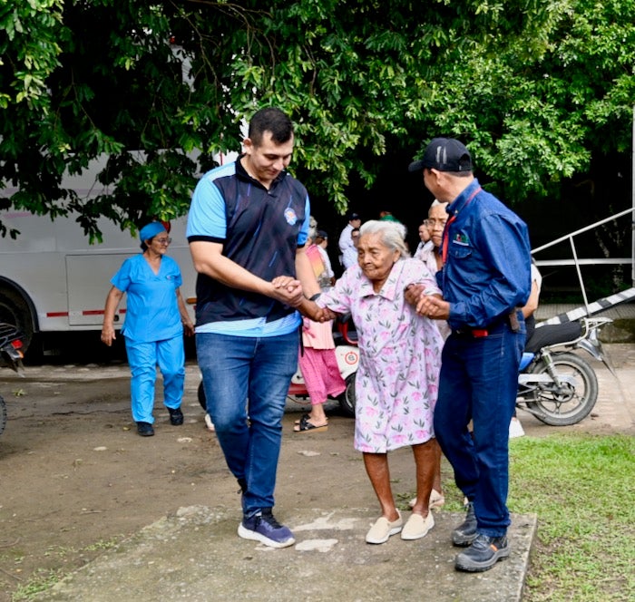 persona anciana siendo guiada por dos personas