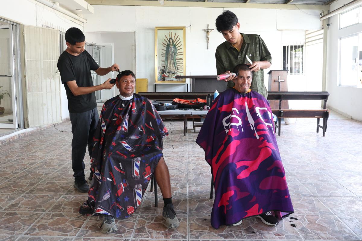 Dos hombres en contexto de movilidad cortandose en cabello