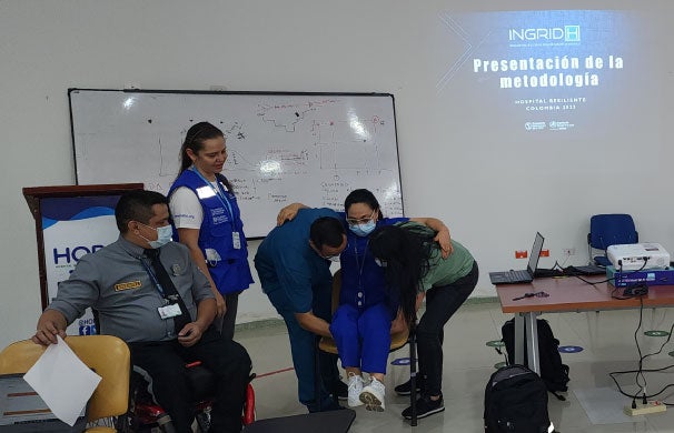 Participantes de taller reunidos en una mesa viendo un computador