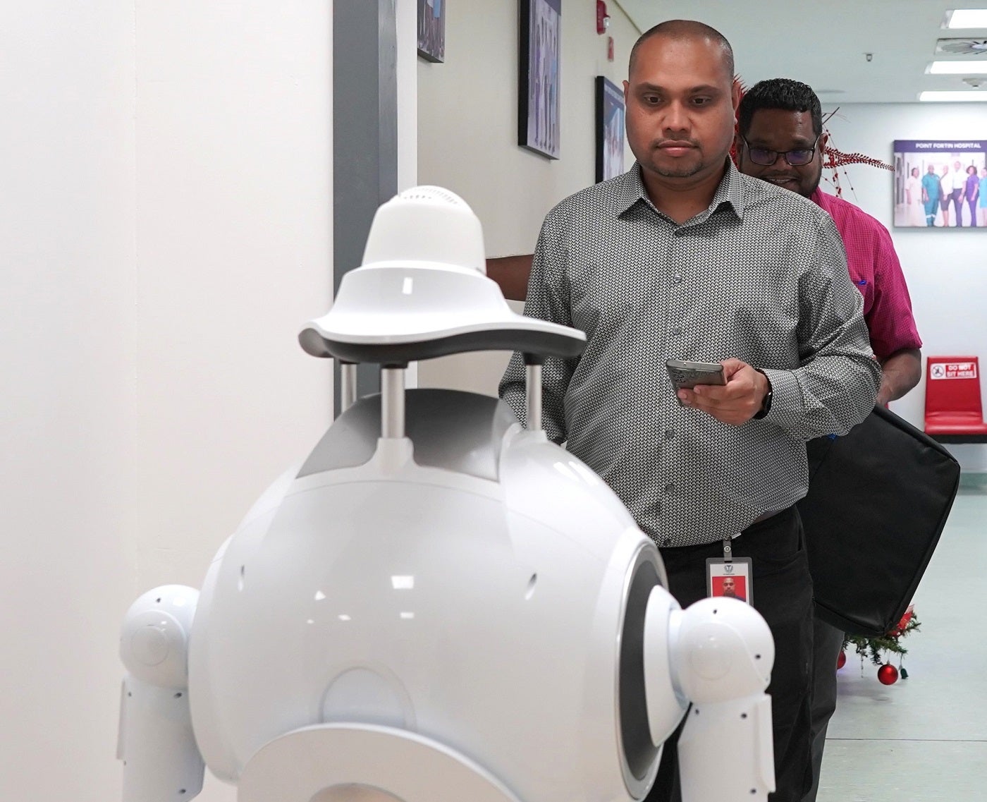 A member of the South-West Regional Health Authority team controls the Humanoid Health Service Robot via the mobile app during the training session at the Point Fortin Hospital