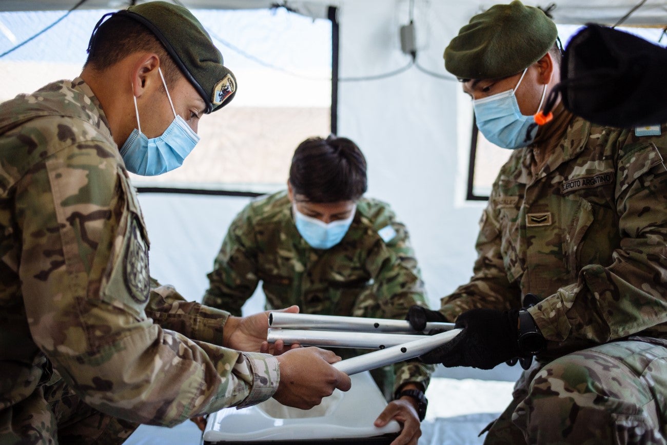 Personal de las fuerzas armando un sanitario dentro de una de las carpas. Foto: OPS/OMS