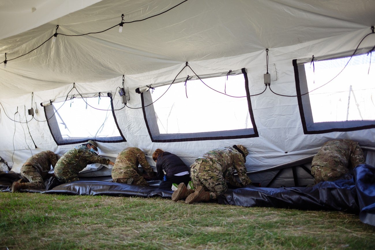 Personal de las fuerzas colocando el piso dentro de una de las carpas. Foto: OPS/OMS