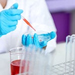 Mano de Bacteriologa inyectando sustancia roja a un recipiente