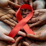 manos de personas de distintas nacionalidades sosteniendo el lazo representativo al Sida