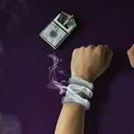 Mano esposada por el humo proveniente de un paquete de cigarrillos y un cenicero sucio.