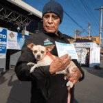 hombre con perro en brazos y la cartilla de vacunación