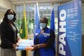 Dr. Michelle Hamilton, Director of the National Public Health Laboratory (left) receives the donation of 6000 Polymerase Chain Reaction (PCR) tests to identify Variants of Concern of COVID-19 (VoC) from Dr. Audrey Morris, Decentralized Regional Advisor, Food and Nutrition (right) at the offices of the Pan American Health Organization/ World Health Organization in Kingston.
