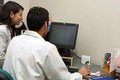 Two health workers looking at a computer monitor.