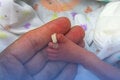 Foot of premature baby on a mother's hand