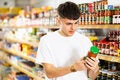 Un hombre joven leyendo la etiqueta frontal del producto (salsa)