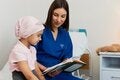 personal de salud mostrándole un libro a una niña con cáncer