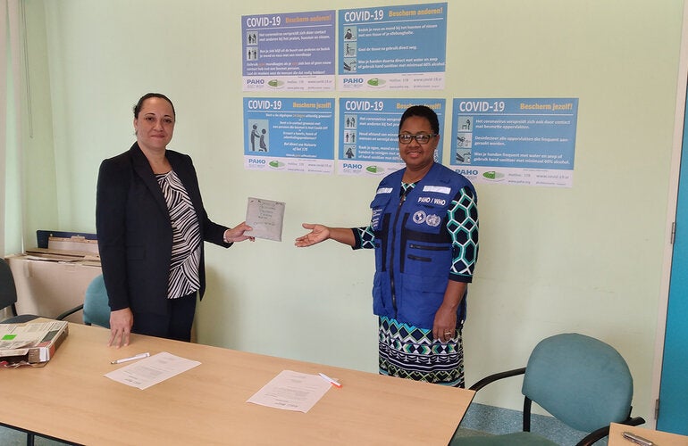Dr. Karen Lewis-Bell hands over the COVID-19 diagnostic test kits to Dr. Cleopatra Jessurun  Director of the ministry of Public Health.