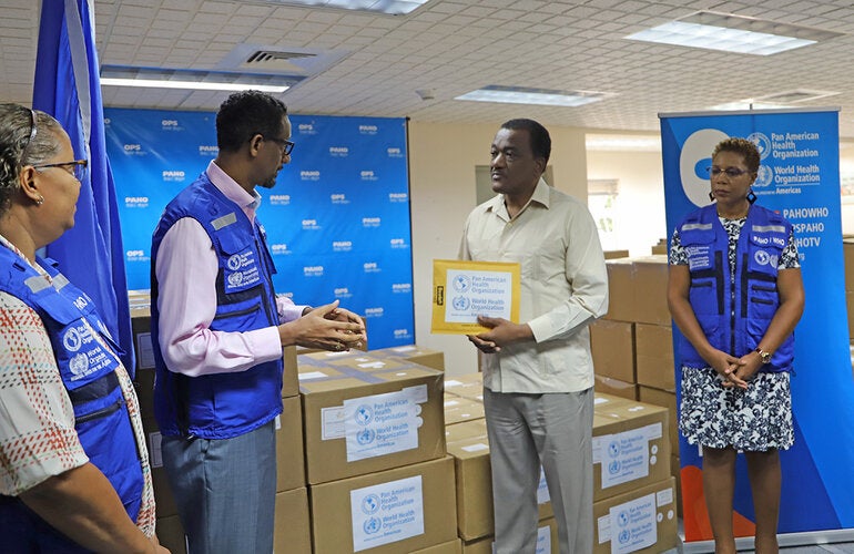 Dr Yitades Gebre – PAHO/WHO Representative to Barbados and the Eastern Caribbean Countries (2nd left) presents PPE and test kits to Lt Col Hon Jeffrey Bostic, Minister of Health and Wellness