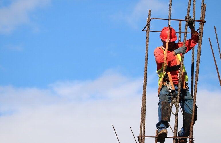 Un trabajador de la construcción se encuentra en una barra de metal.