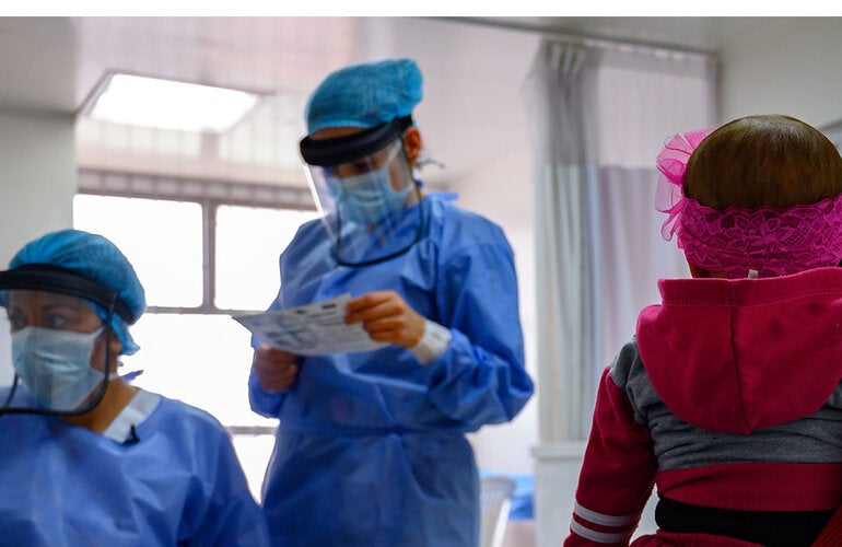 Health personnel reviewing a girl's vaccination card