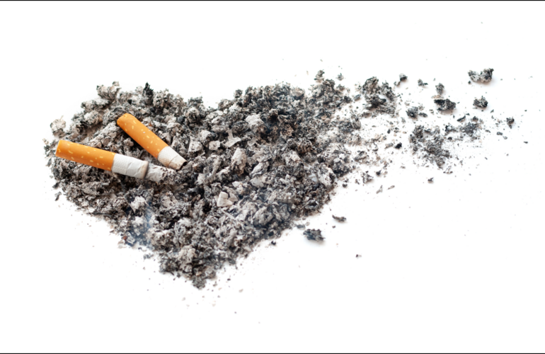 Imagen de una colilla apagándose en un conjunto de ceniza con forma de corazón. A la derecha, parte del corazón de ceniza se deshace