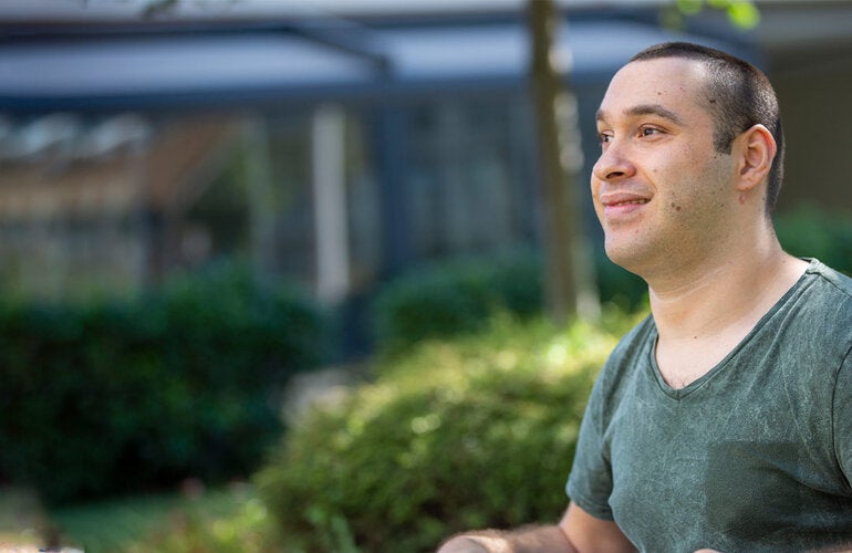 Man with disability sitting on a wheelchair outdoors smiling