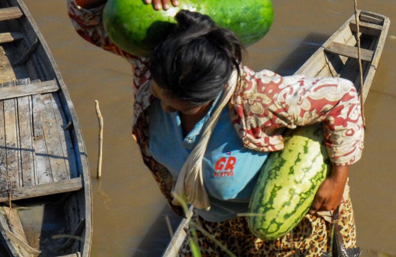 Woman with watermelons and fish in hand