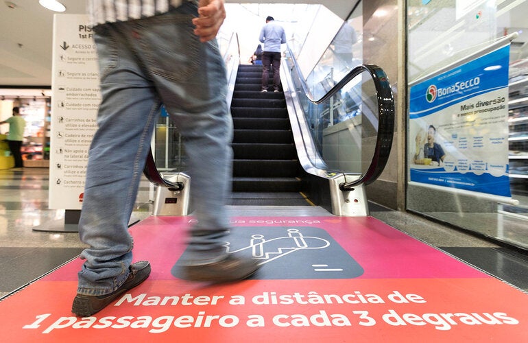 person approaching an escalator with physical distancing recommendations