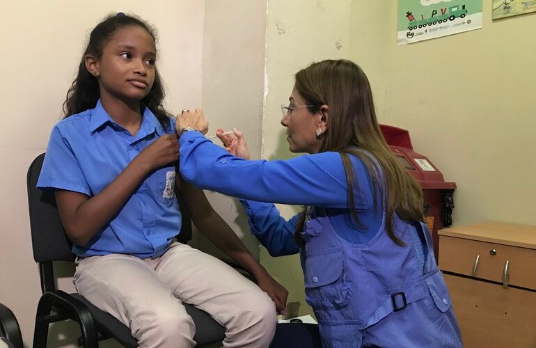 Representante vacuna a una asistente