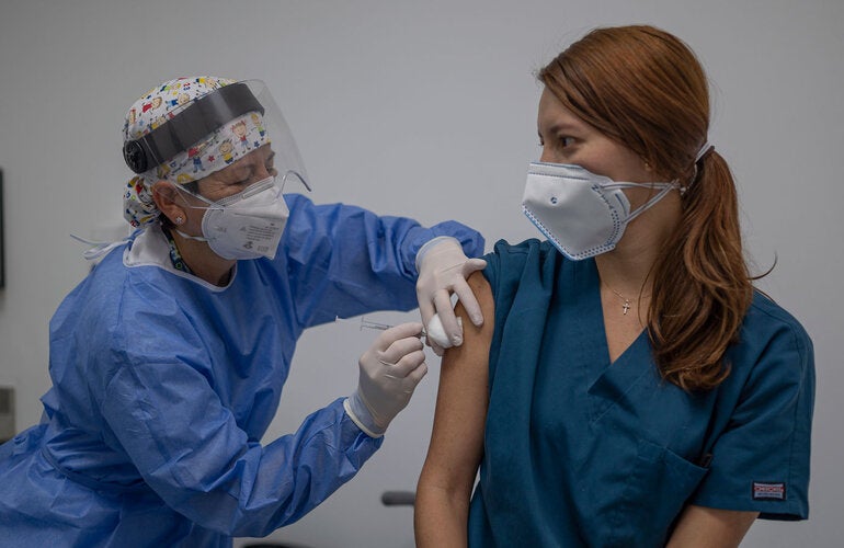 Enfermera aplicando vacuna a mujer