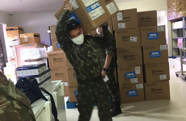Militares da Força Tarefa da Operação Acolhida, no Brasil, carregam testes para diagnóstico de COVID-19 doados pela OPAS