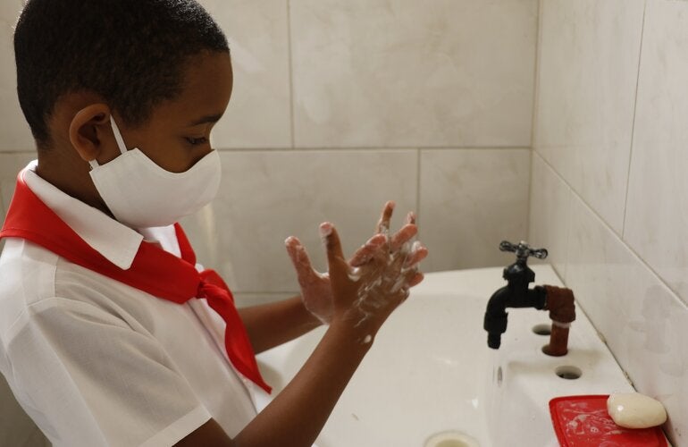 Niño se lava las manos en escuela cubana