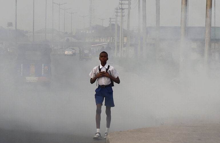 Niño caminando en ciudad con aire contaminado.