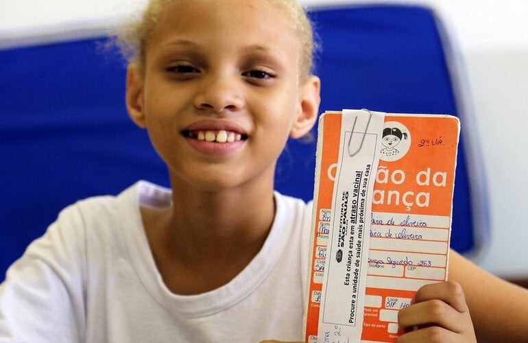 Una niña muestra su certificado de vacunación contra el VHP en Brasil