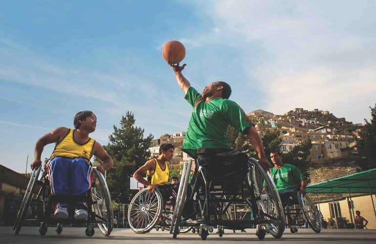 Group of young men playing basketball on wheel chairs