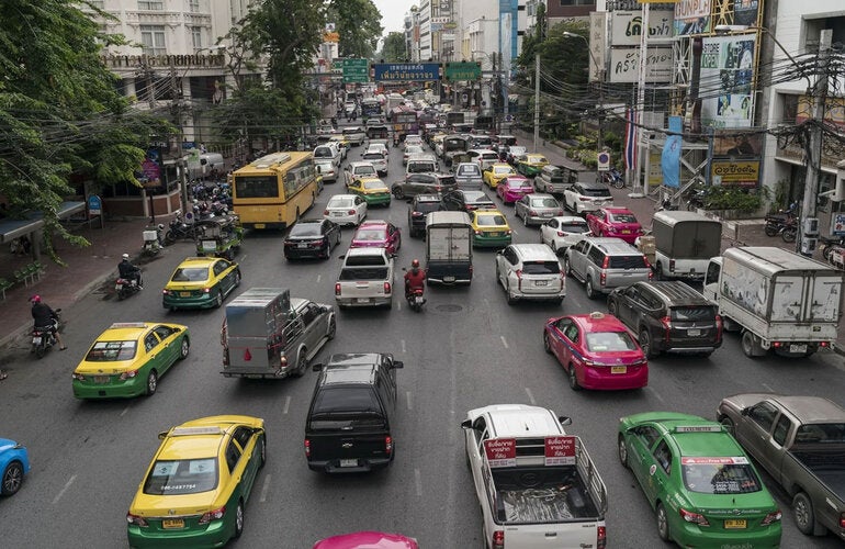 Busy urban street filled with cars and vehicles circulating in the same direction. 