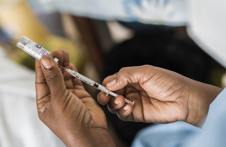 Trabajador de salud con una vacuna contra la COVID-19 en la mano