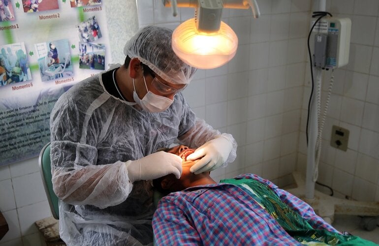 Profissional de saúde realiza procedimento de saúde bucal em homem jovem