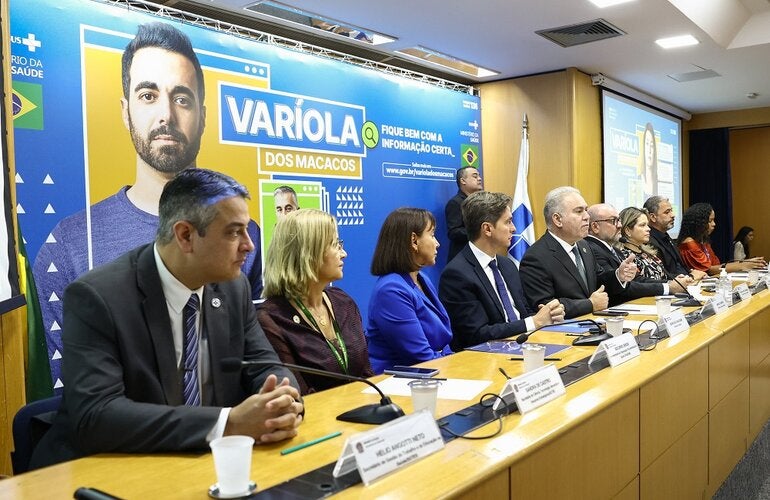 Mesa da cerimônia de lançamento da campanha de prevenção à varíola dos macacos